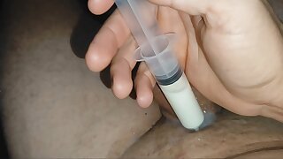Reintroduction of the boy's load into the cock with the syringe.